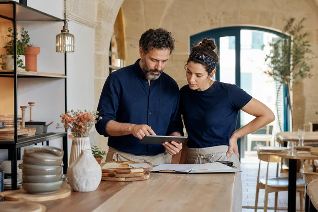 Restaurant owners reviewing sales and supplier records before opening
