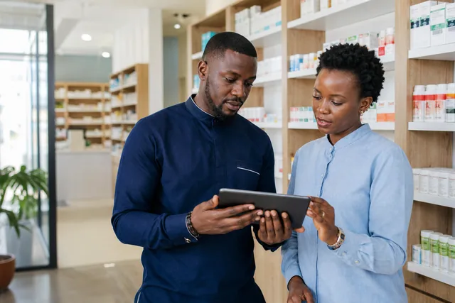 A community pharmacy team reviewing medicine stock and expiry records